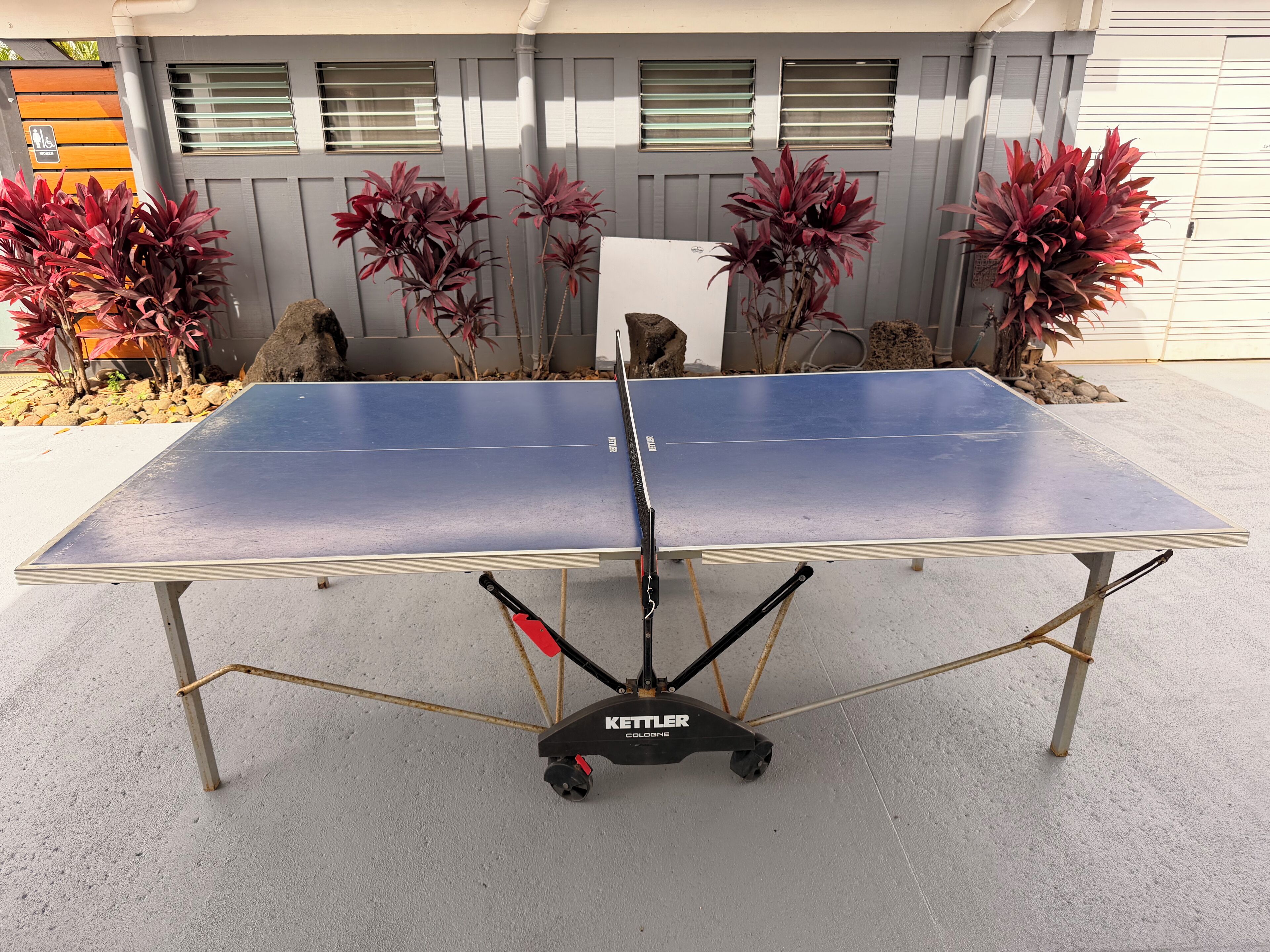 Una mesa de ping pong con un soporte Kettler Colonia en un entorno exterior.