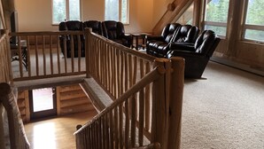 A wooden interior with a staircase, leather chairs, and large windows. - King's Deer Lodge in Denali  (Denali)