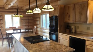 A kitchen with wooden cabinets, a granite countertop, a built-in oven, and pendant lighting. - King's Deer Lodge in Denali  (Denali)