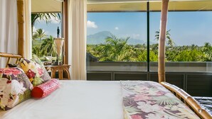 Une chambre avec un lit, une table et une vue sur la verdure et les montagnes.