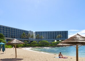 A beach with thatched umbrellas, a sandy shore, and a modern hotel building in the background. - Closest to Hotel and Beach, Split Air Conditioners (Kahuku)