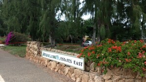 A sign for Kuilimaar Estates East, a stone wall, and red flowers. -  Closest to Hotel and Beach, Split Air Conditioners (Kahuku)