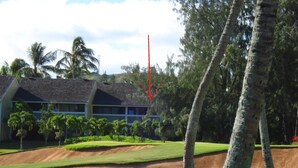 A golf course with a building in the background, palm trees, and a clear sky. -  Closest to Hotel and Beach, Split Air Conditioners (Kahuku)