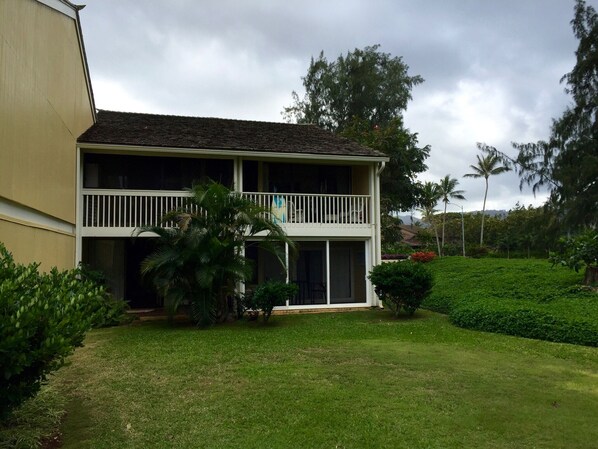 A two-story building with a balcony, surrounded by lush greenery and palm trees. - Closest to Hotel and Beach, Split Air Conditioners (Kahuku)