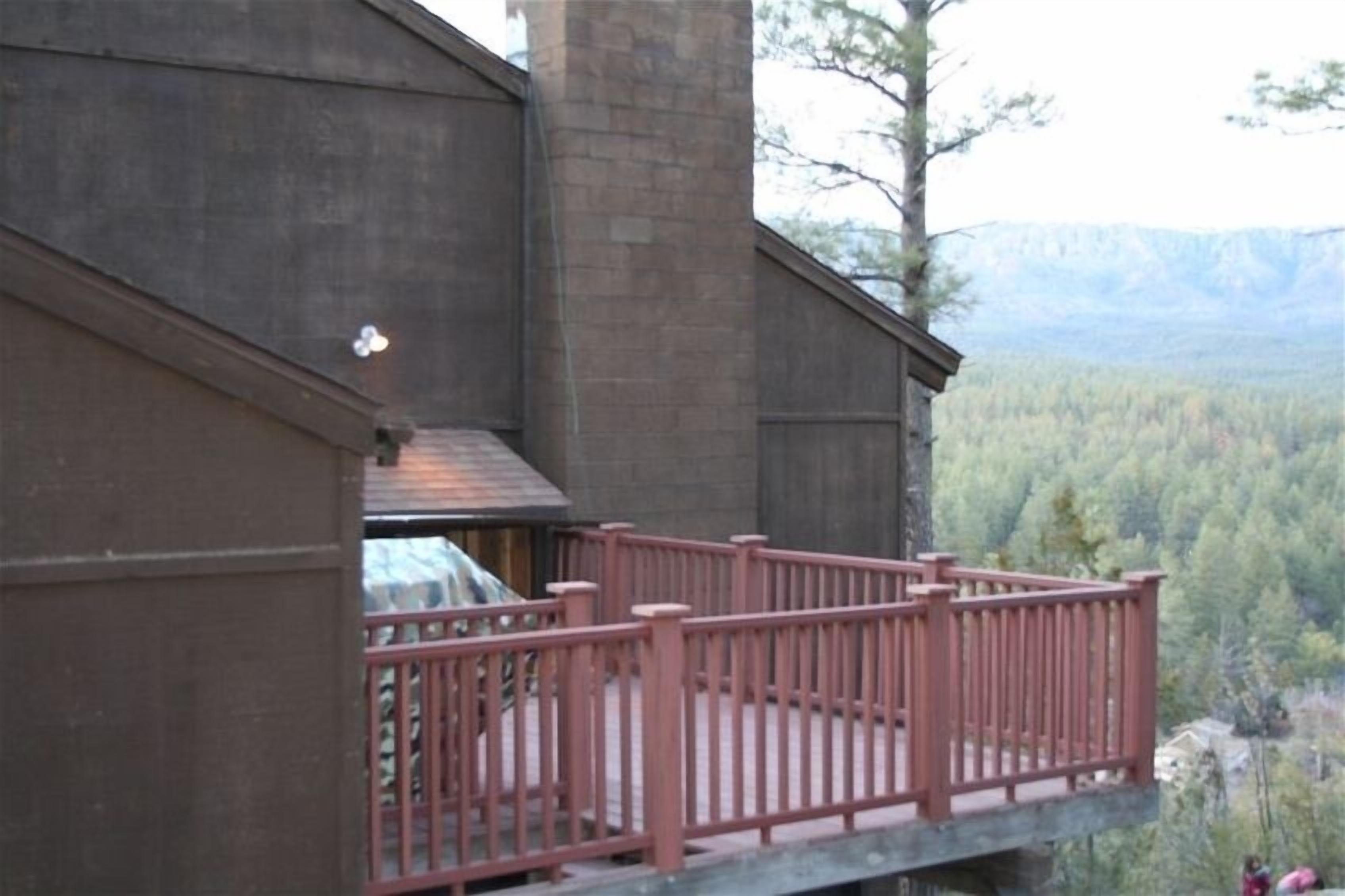 Puinen rakennus, jossa on parveke, jolta avautuu näkymä metsäiseen laaksoon.
