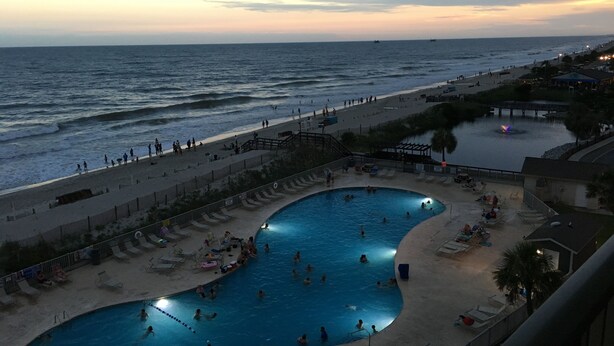 Ein Poolbereich am Strand mit Blick auf das Meer und einen Steg.