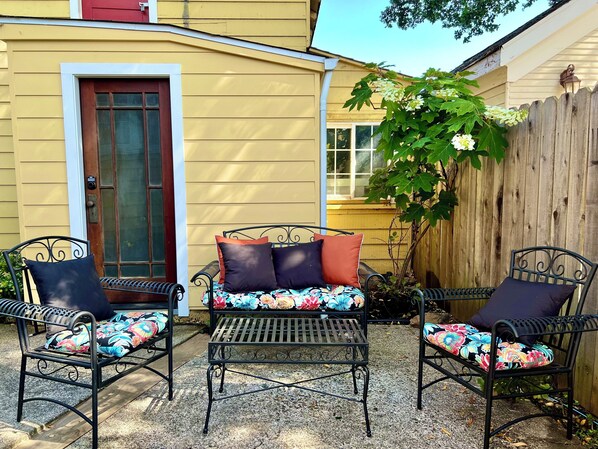Un patio con dos sillas de metal y una mesa, cada una con cojines estampados.