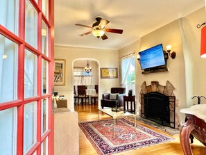 Una sala de estar con chimenea, televisor montado en la pared y comedor con mesa y sillas.