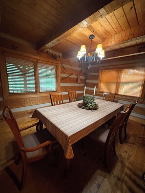 Une salle à manger en bois, avec une table, des chaises et un lustre.