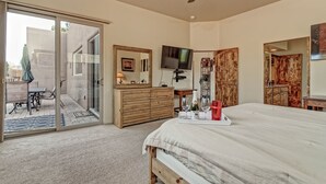 Habitació amb llit, una petita taula de nit, televisió i una finestra corredissa que dona a una zona exterior.