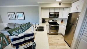 A modern kitchen with white cabinets, stainless steel appliances, and a wooden floor. - Ocean View 2BR - Pool, Private Beach & Near Parks (Tavernier)