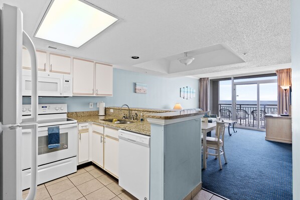 A modern kitchen with white appliances, a blue accent wall, and a balcony with a view.