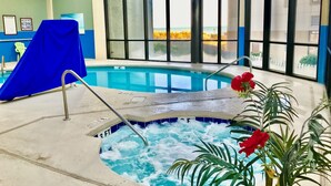 Une piscine intérieure avec un jacuzzi, de grandes fenêtres et une vue sur la plage.