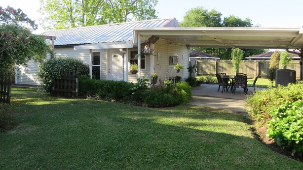 A house with a covered patio, a fenced yard, and a lawn. - Mardi Gras Cottage, 4 km to French Quarter (ARABI)