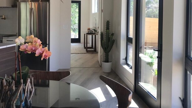 Eine moderne Küche mit einem Glastisch, Holzkästen, einer besonderen Leuchte und Blick ins Freie.
