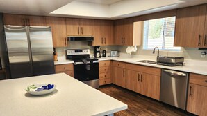 A modern kitchen with wooden cabinets, stainless steel appliances, and a white countertop. - Papago Pines - 5 bedrooms, EACH WITH ATTACHED EN SUITE BATHROOM & Smart TV (Munds Park)
