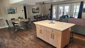 A modern kitchen with a central island, dining area with chairs, and a living area with a couch. - Papago Pines - 5 bedrooms, EACH WITH ATTACHED EN SUITE BATHROOM & Smart TV (Munds Park)