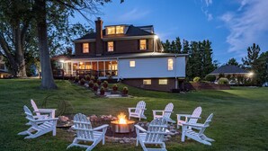A large two-story house with a covered porch and a fire pit in the front yard. - 240' Private Beachfront @Kent Island Love Point - Great for Families (stevensville)