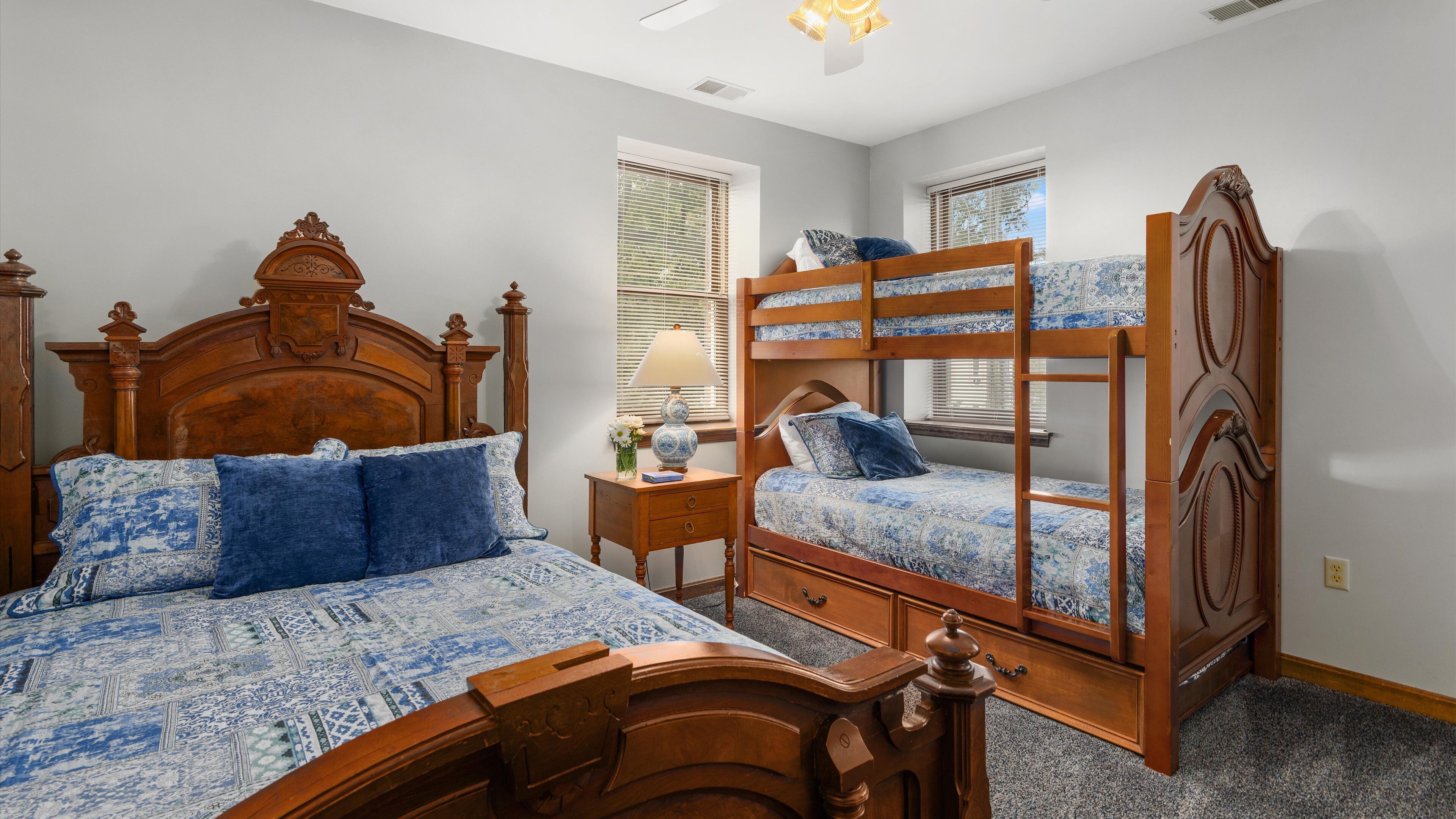 A bedroom with a large bed, a smaller bed, a nightstand, and a window with blinds.