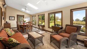 A spacious living room with a large window, a dining area, and a cozy seating arrangement. - 240' Private Beachfront @Kent Island Love Point - Great for Families (stevensville)