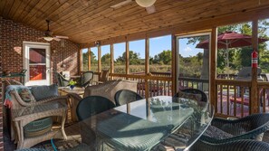 Un patio cubierto con mobiliario de mimbre, una mesa de vidrio y un muro de ladrillo.