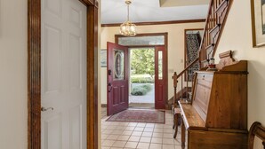A wooden staircase with a handrail, a red door, and a patterned rug leading to a door with a glass panel. - 240' Private Beachfront @Kent Island Love Point - Great for Families (stevensville)