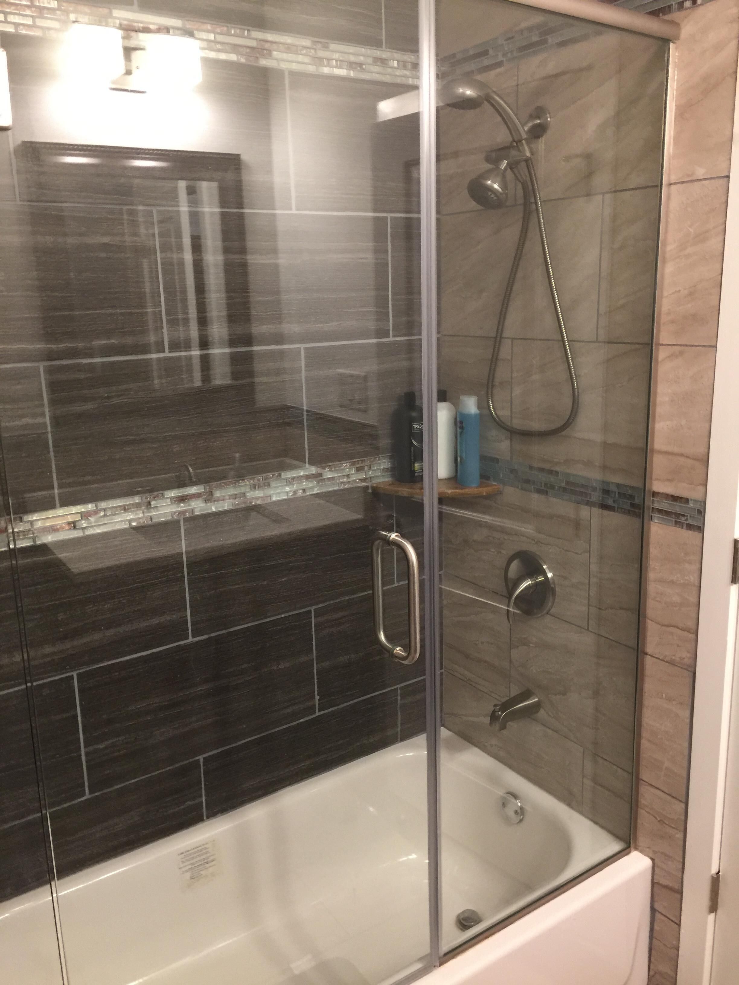 Une douche fermée par des parois en verre, équipée d’un pommeau de douche à main, d’un autre pommeau de douche à main et d’un troisième pommeau de douche à main.