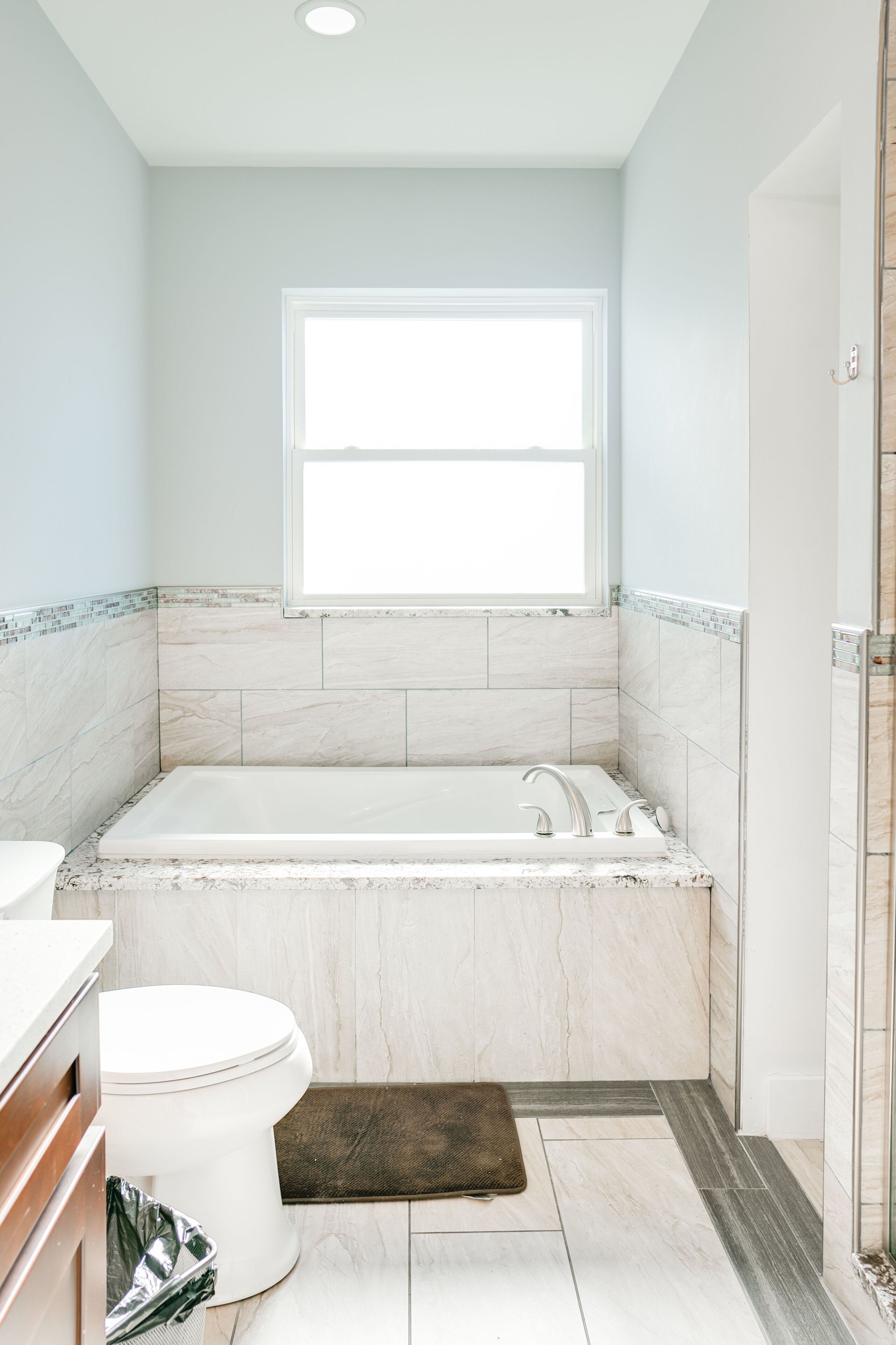 A bathroom with a bathtub, toilet, and a window.