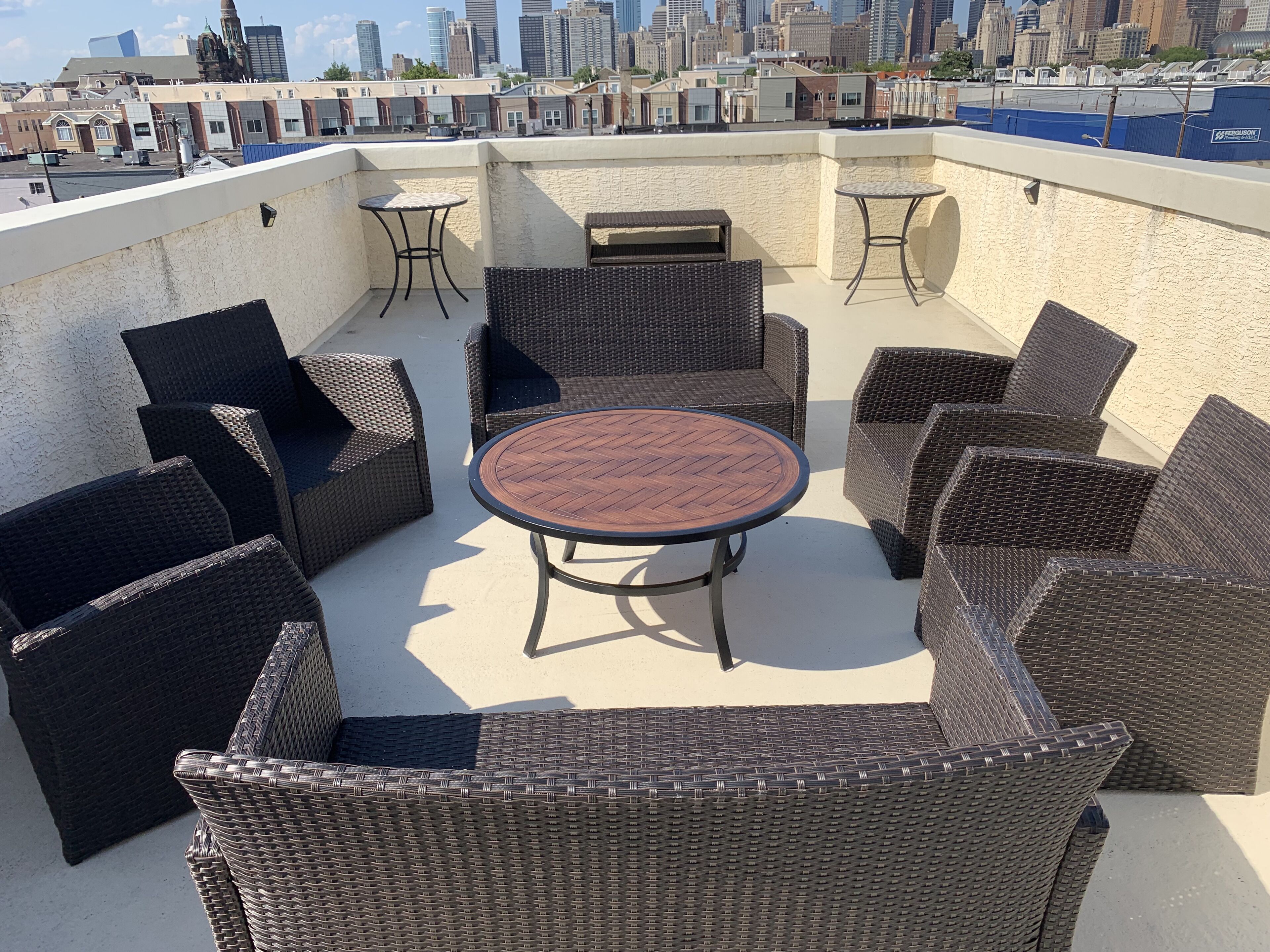 Eine Dachterrasse mit Korbmöbeln, einem runden Tisch und einem Grill.
