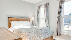 A neatly made bed with a patterned bedspread, a wooden headboard, and a bedside table with a lamp. - Spacious 4BD/3Bath, HUGE Rooftop deck and patio. Amazing Views! (Philadelphia)