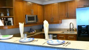 A kitchen with wooden cabinets, a microwave, a sink, and a refrigerator. - Spacious condo with gulf view (Pensacola Beach)