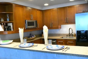 A kitchen with wooden cabinets, a microwave, a sink, and a refrigerator.