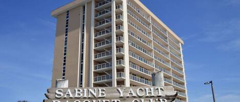 Un edificio alto con un letrero que dice 'Sabine Yacht Racquet Club 330 FT Pickens Rd'.