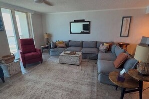 A living room with a red chair, grey sofa, and a patterned rug.