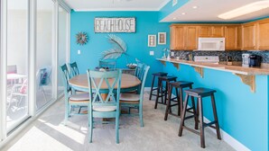 Eine Küche mit blauer Wand, Holzschränken, einer weißen Mikrowelle und einer Bar mit Hockern.
