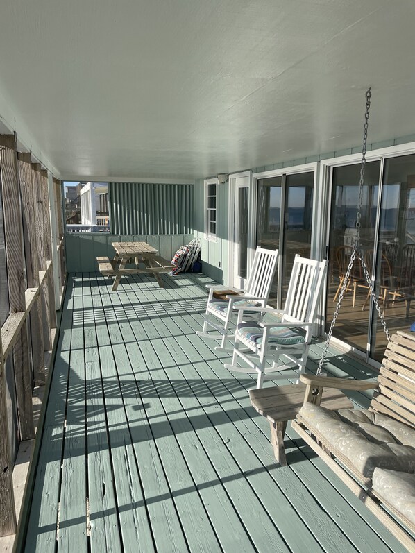 A covered outdoor deck with wooden flooring, white rocking chairs, and a swing. - Beachfront 3 bedroom 2 bath pet friendly w/fee-Special rates on Winter weekends (Surf City)