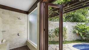 Ein Badezimmer mit Dusche, Badewanne und einer Glastür zum Garten.