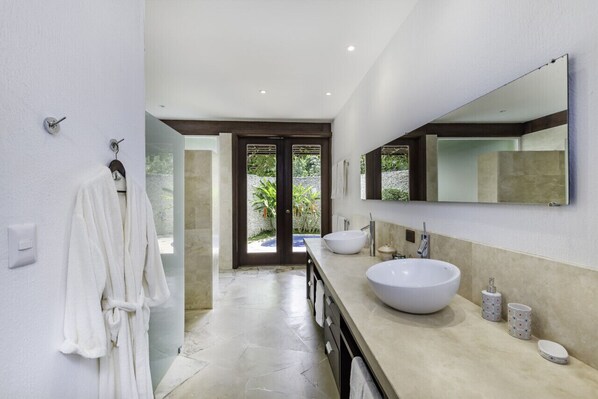Un baño moderno con un espejo grande, dos lavamanos y un perchero para bata.
