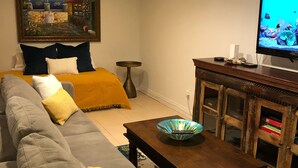 Una sala de estar con un sofá, una mesa de centro, una televisión y un cuadro en la pared.