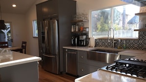 A modern kitchen with stainless steel appliances, a large window, and a herringbone-patterned backsplash.