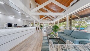 A spacious indoor area with wooden flooring, a long counter, and a seating area with a sofa and armchairs. - ❤️ Stunning Reno| Amazing Ocean View 💦❤️ (Lahaina-Kaanapali)