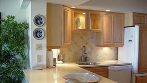 Una cocina moderna con armarios de madera, un lavamanos de acero inoxidable y una encimera blanca.