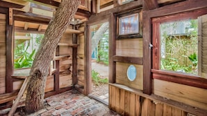 A rustic wooden room with a brick floor, wooden beams, and a large tree trunk. - Eastern Lake Lakefront! Easy access to the Gulf! Pirate Ship & Treehouse! (Santa Rosa Beach)