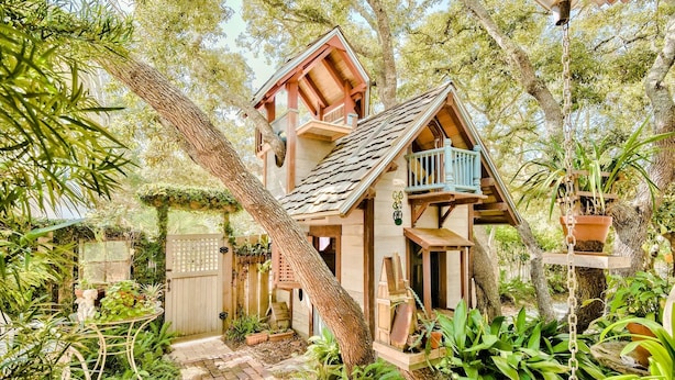 A wooden house with a balcony, surrounded by lush greenery and a brick pathway. - Eastern Lake Lakefront! Easy access to the Gulf! Pirate Ship & Treehouse! (Santa Rosa Beach)