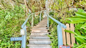 A wooden staircase with metal railings, surrounded by lush greenery. - Eastern Lake Lakefront! Easy access to the Gulf! Pirate Ship & Treehouse! (Santa Rosa Beach)