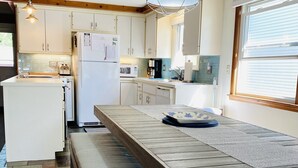 Eine moderne Küche mit Holztisch, Bank und Pendelleuchten.