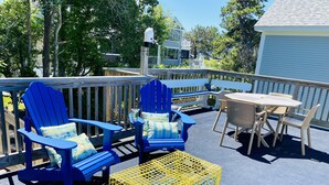 Eine Terrasse mit blauen Adirondack-Stühlen, einer gelben Krabillenfalle und einem Holztisch mit Stühlen.