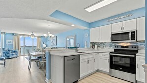 A modern kitchen with white cabinets, a black microwave, and a stainless steel oven. - Beach Chic Oceanfront Condo, Jacuzzi Tub, Lazy River | Crescent Shores - N 1203 (North Myrtle Beach)