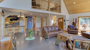 Een ruime loft met een eethoek, een woonkamer met een bruine leren bank en een keuken met hangende pannen.