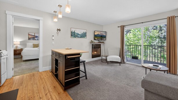 Een moderne woonkamer met een open haard, een balkon met gordijnen en een eethoek met een tafel en stoelen.